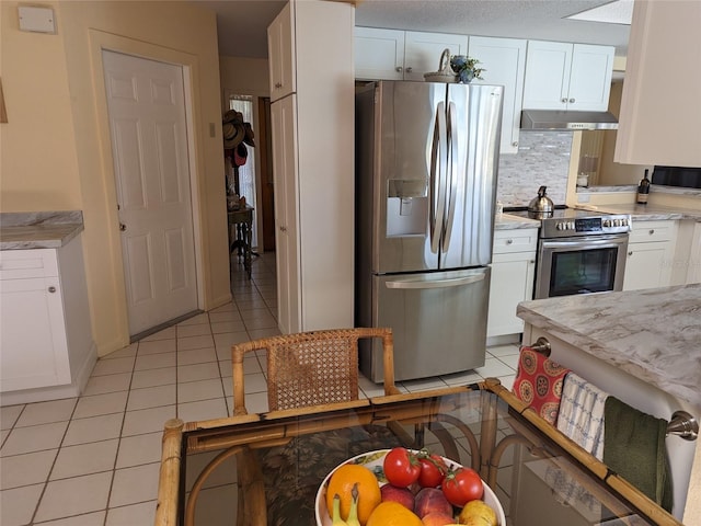 kitchen with stainless steel appliances, white cabinets, backsplash, and light tile floors