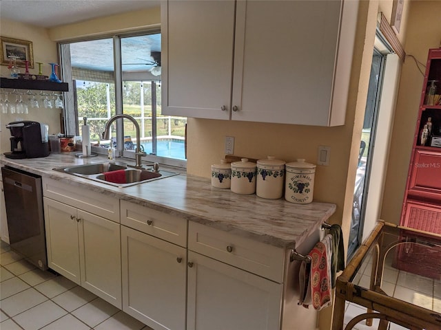 kitchen with light tile flooring, light stone countertops, stainless steel dishwasher, white cabinets, and sink