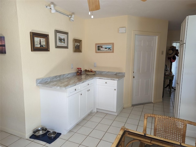 kitchen with white cabinetry, light tile flooring, and ceiling fan