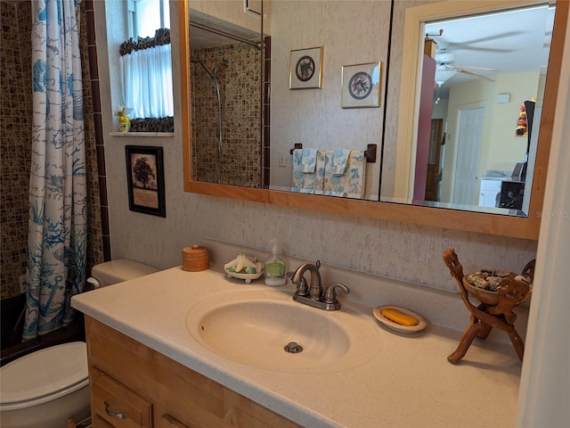 bathroom with ceiling fan, toilet, and vanity with extensive cabinet space