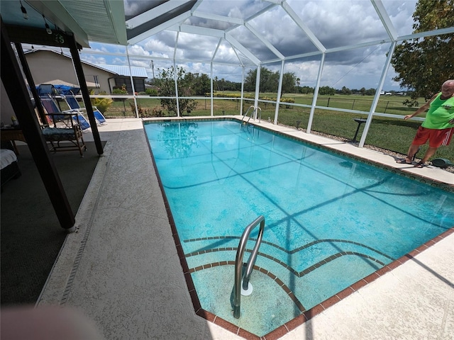 view of pool with a patio area, a lawn, and a lanai