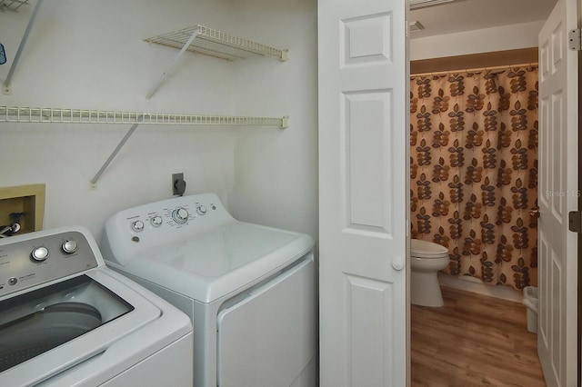 laundry area with independent washer and dryer and wood-type flooring