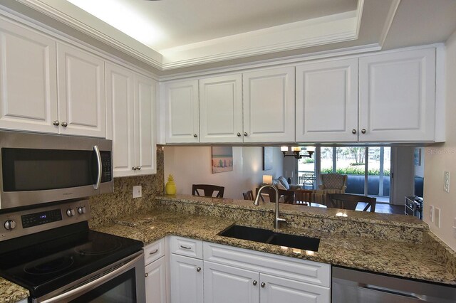 kitchen with kitchen peninsula, appliances with stainless steel finishes, crown molding, sink, and white cabinets