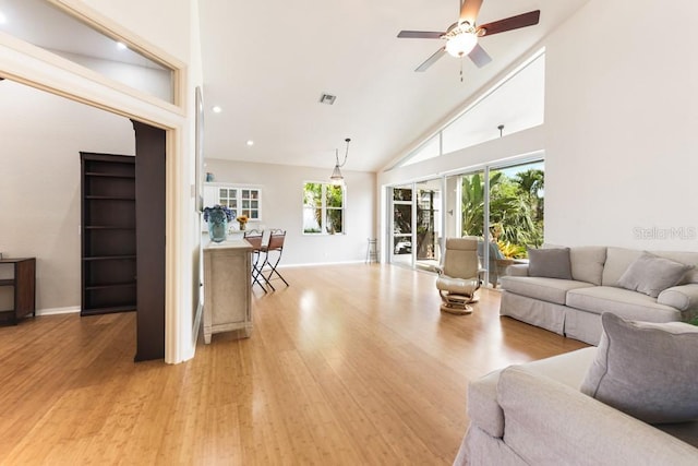 living room with ceiling fan, light hardwood / wood-style flooring, high vaulted ceiling, and a healthy amount of sunlight