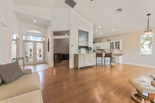 living room with a chandelier, french doors, hardwood / wood-style flooring, and high vaulted ceiling