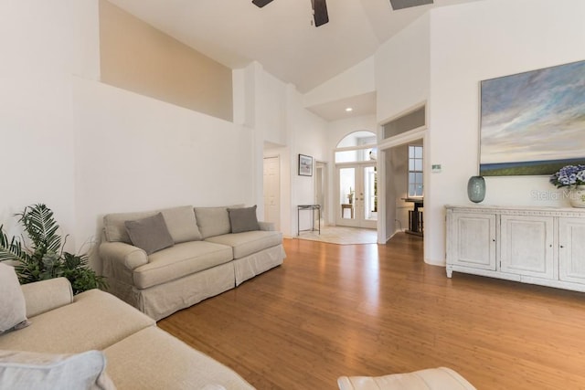 living room with ceiling fan, light wood-type flooring, high vaulted ceiling, and french doors