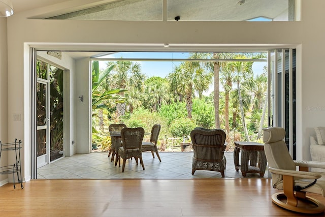 doorway to outside with light hardwood / wood-style floors and vaulted ceiling