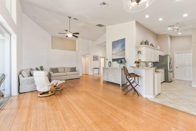 living room featuring light hardwood / wood-style floors, high vaulted ceiling, and ceiling fan