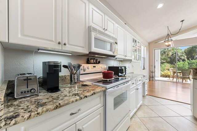 kitchen featuring white appliances, pendant lighting, white cabinetry, lofted ceiling, and light tile patterned flooring