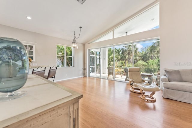 living room with french doors, light hardwood / wood-style flooring, a wealth of natural light, and vaulted ceiling