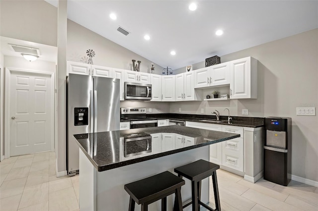 kitchen with sink, stainless steel appliances, a kitchen island, a breakfast bar, and white cabinets