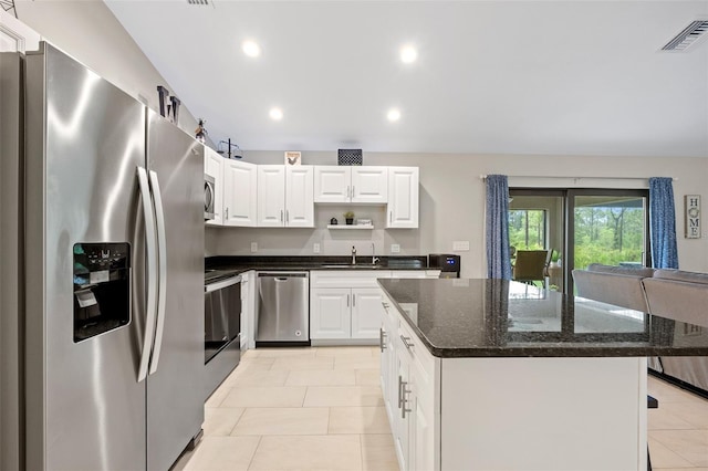 kitchen featuring a center island, dark stone counters, white cabinets, sink, and stainless steel appliances