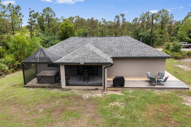 rear view of house with a lawn, glass enclosure, and a patio