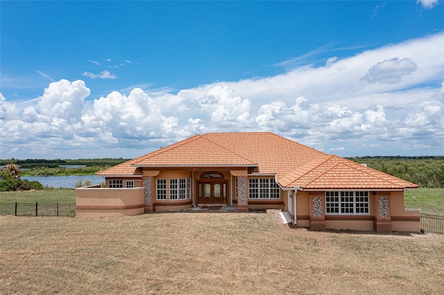 view of front of home with french doors, a water view, and a front lawn