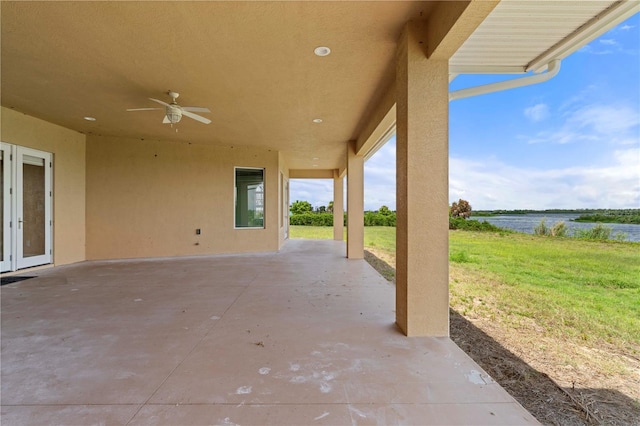 view of patio featuring ceiling fan, french doors, and a water view