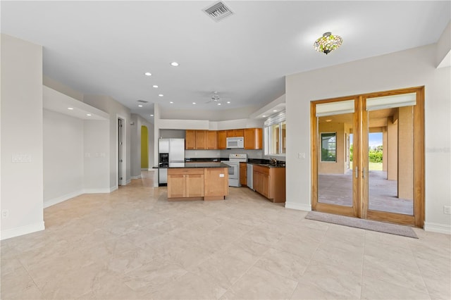 kitchen with a center island, white appliances, french doors, sink, and ceiling fan