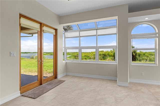 interior space with light tile patterned floors and a water view