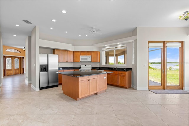 kitchen with ceiling fan, a center island, white appliances, and a healthy amount of sunlight