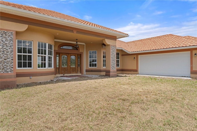 doorway to property with french doors, a garage, and a lawn