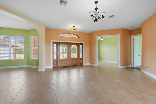 entrance foyer with ceiling fan with notable chandelier, a wealth of natural light, and light tile patterned flooring