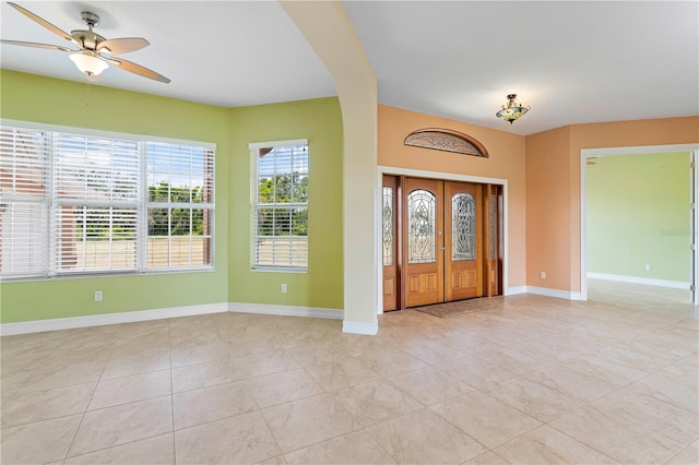 tiled foyer entrance with ceiling fan and french doors