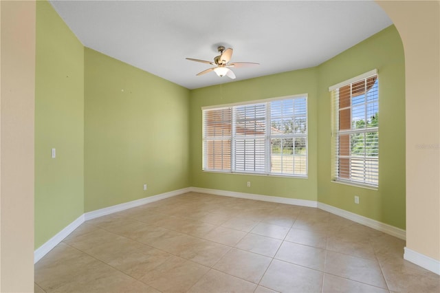 tiled empty room with ceiling fan and plenty of natural light