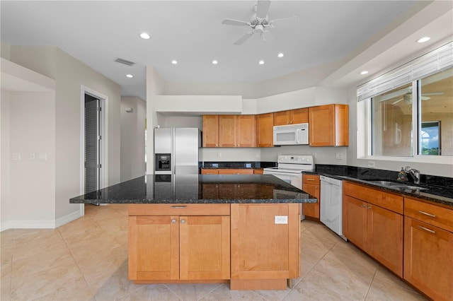 kitchen with white appliances, a kitchen island, dark stone countertops, and sink