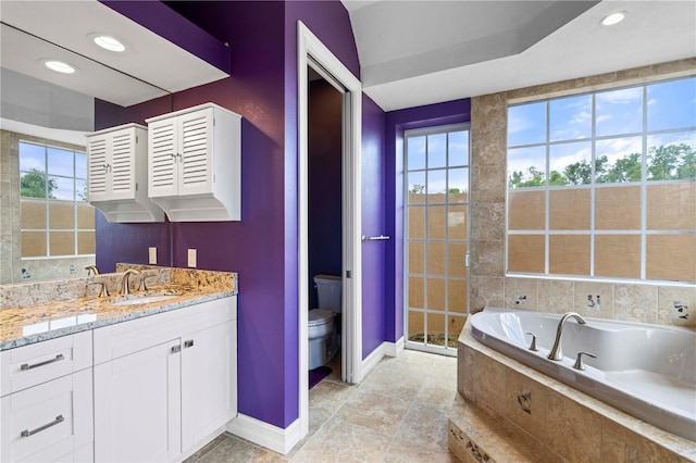 bathroom with tile patterned floors, vanity, toilet, and tiled tub