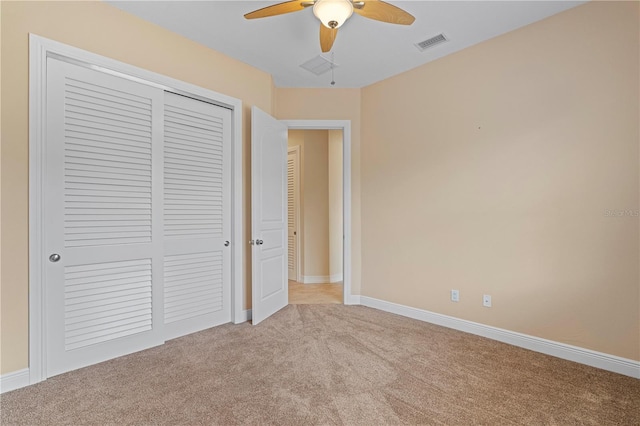 unfurnished bedroom featuring light carpet, a closet, and ceiling fan