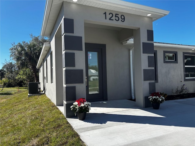 property entrance featuring central AC unit and a lawn