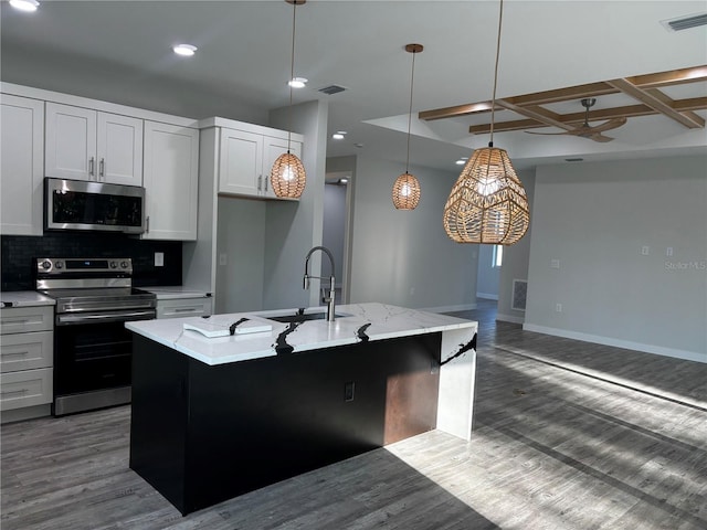 kitchen with a kitchen island with sink, coffered ceiling, sink, appliances with stainless steel finishes, and white cabinetry