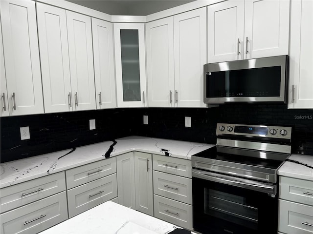 kitchen with white cabinets, decorative backsplash, and appliances with stainless steel finishes