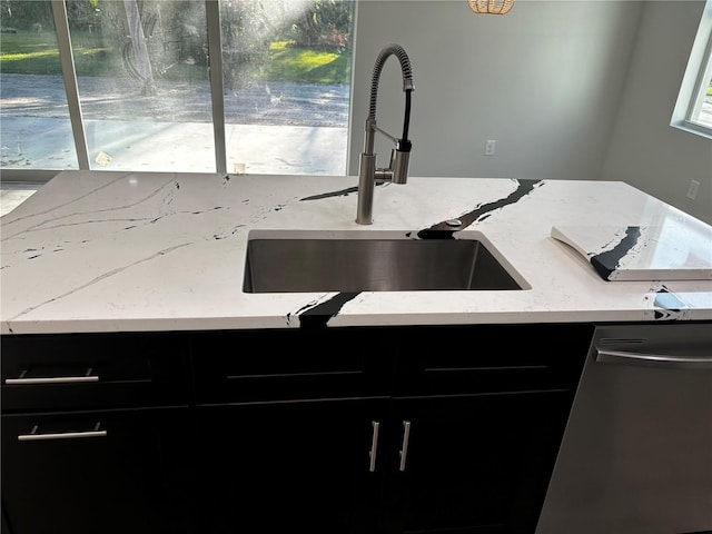 room details featuring light stone countertops, stainless steel dishwasher, and sink