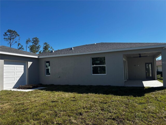 back of house featuring a lawn, ceiling fan, a garage, and a patio