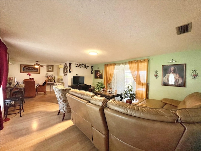 living room featuring wood-type flooring, ceiling fan, and a textured ceiling