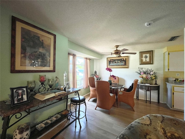 dining room featuring hardwood / wood-style flooring, ceiling fan, and a textured ceiling