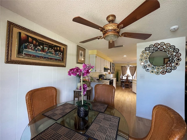 dining area featuring a textured ceiling, ceiling fan, and hardwood / wood-style floors