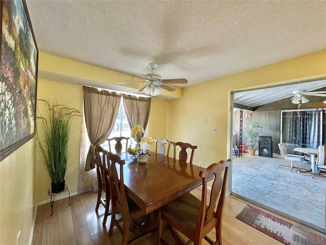 dining room with ceiling fan, a textured ceiling, hardwood / wood-style flooring, and lofted ceiling