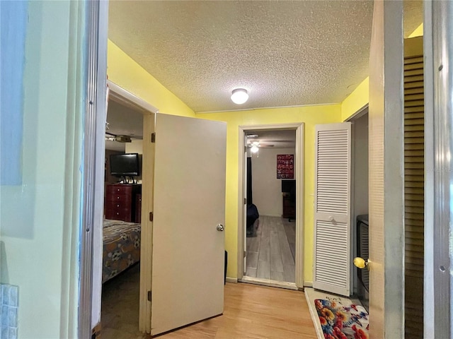 corridor featuring light hardwood / wood-style flooring and a textured ceiling