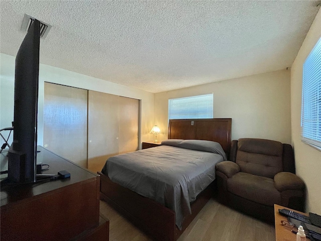 bedroom featuring dark hardwood / wood-style floors, a closet, and a textured ceiling