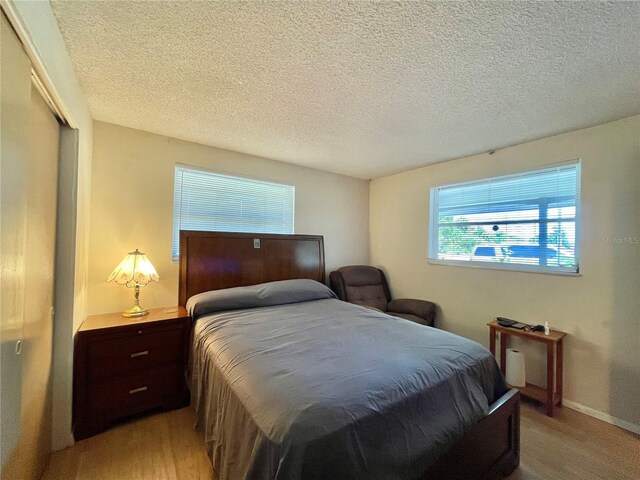 bedroom with a closet, a textured ceiling, and hardwood / wood-style flooring