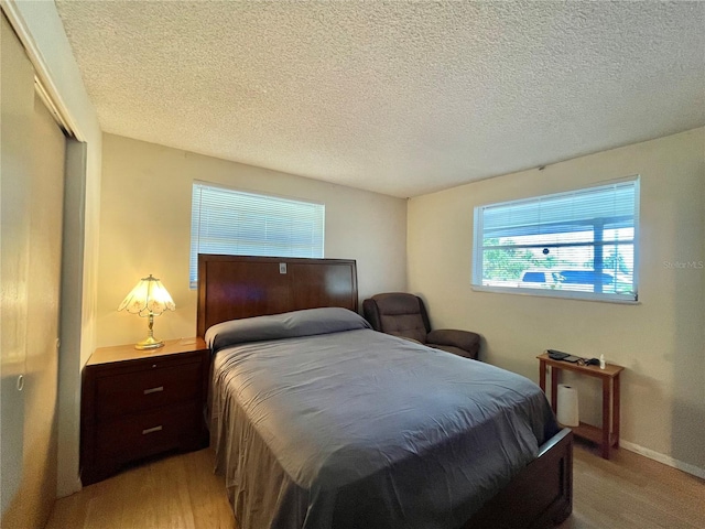 bedroom with light hardwood / wood-style floors, a closet, and a textured ceiling