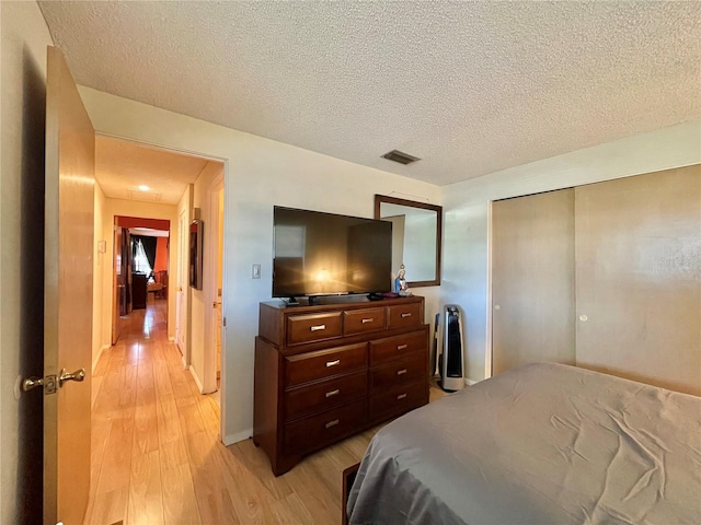 bedroom with a closet, light hardwood / wood-style flooring, and a textured ceiling