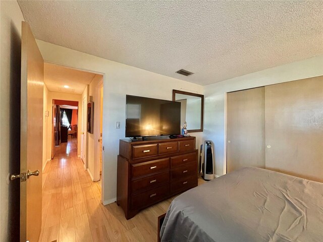 bedroom featuring a textured ceiling, light hardwood / wood-style floors, and a closet