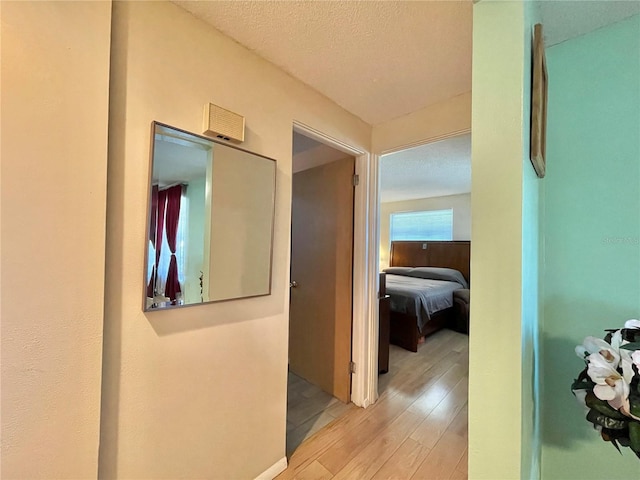 hall featuring light hardwood / wood-style floors and a textured ceiling