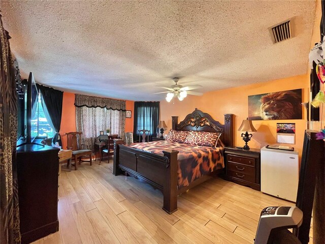 bedroom with a textured ceiling, light wood-type flooring, and ceiling fan