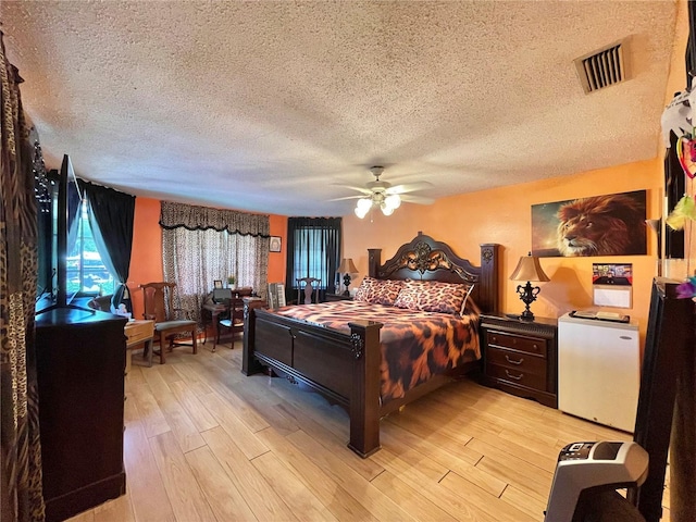 bedroom with ceiling fan, light hardwood / wood-style floors, and a textured ceiling