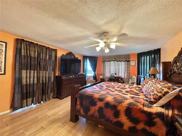 bedroom with ceiling fan, light hardwood / wood-style floors, and a textured ceiling