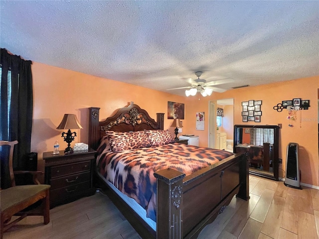 bedroom with a textured ceiling, ceiling fan, and hardwood / wood-style floors