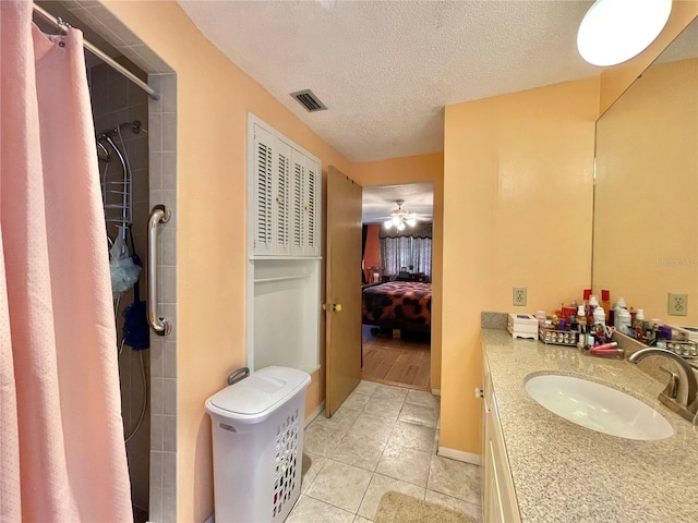 bathroom with a textured ceiling, tile flooring, vanity, and ceiling fan